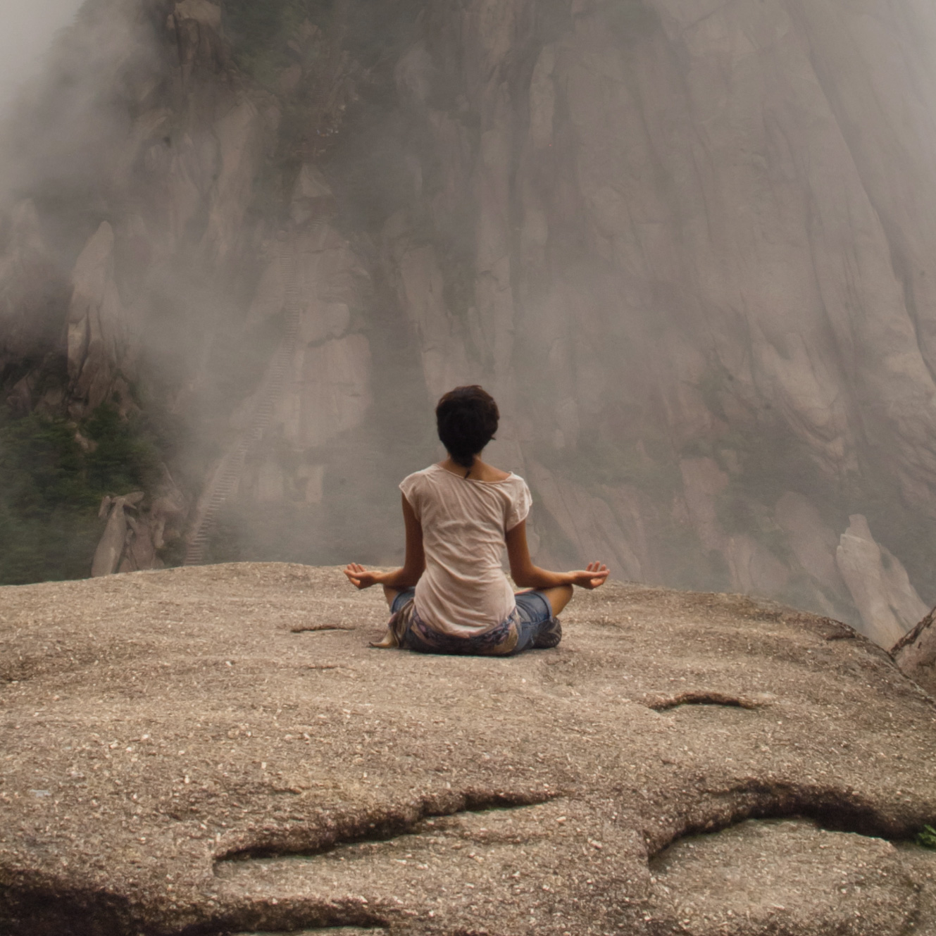 woman meditating on large rock